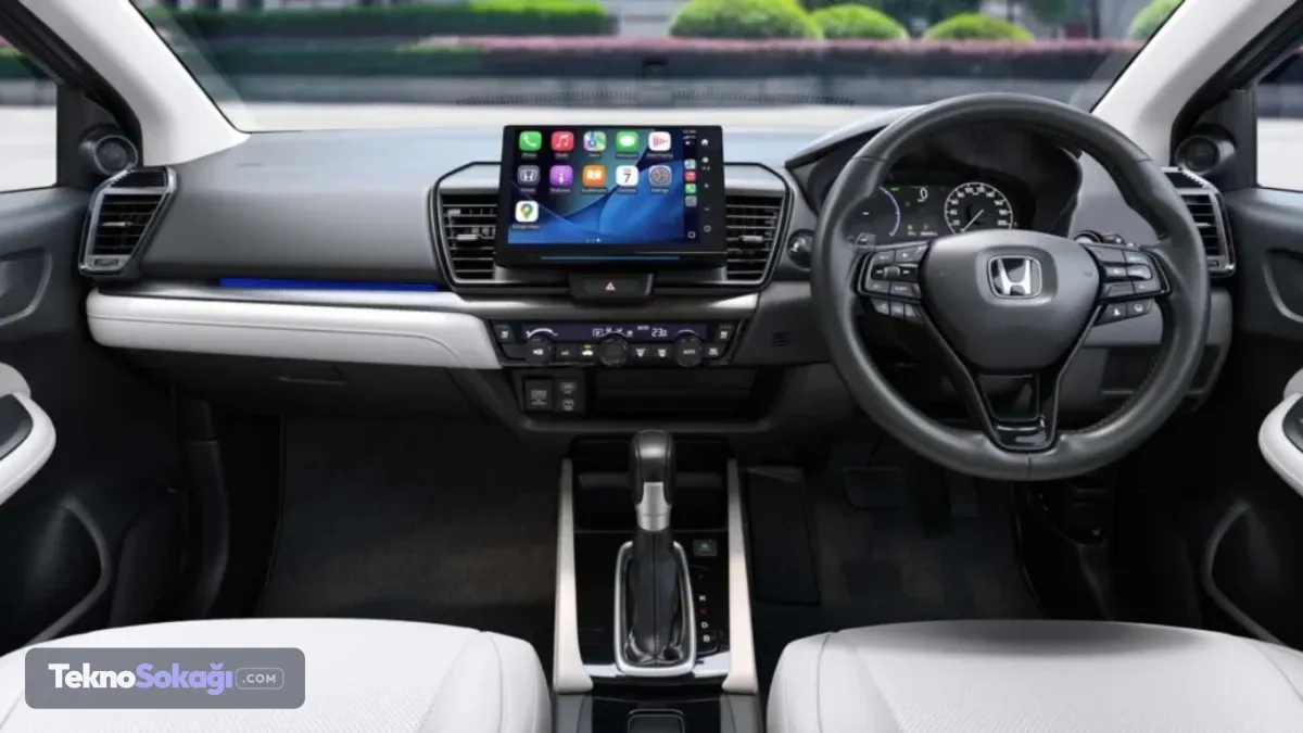 İç mekanda teknoloji devrimi: Fiziksel butonlar unutulmadıYeni Honda City’nin kapısını açtığınızda sizi tamamen modernize edilmiş bir konsol karşılıyor. Konsolun tam merkezinde, dışa doğru çıkıntılı ve ergonomik şekilde konumlandırılmış 10,1 inçlik geniş bir multimedya ekranı yer alıyor. Bu gelişmiş sistem, sürücülere kablosuz Apple CarPlay ve Android Auto desteğini standart olarak sunuyor.Birçok markanın aksine, sürücülerin sürüş esnasında konforunu ve güvenliğini artırmak adına klima ve temel kontroller için çok sayıda fiziksel butonun korunmuş olması da otomobil eleştirmenlerinden tam not aldı.